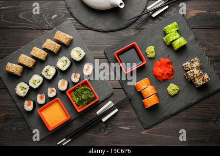 Schiefer Platten mit verschiedenen Sätzen von Sushi am Holztisch Stockfoto