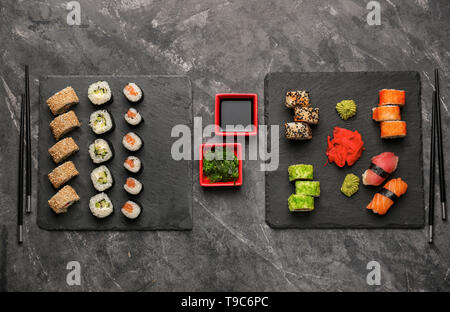 Schiefer Platten mit verschiedenen Sätzen von Sushi auf dunklen Tabelle Stockfoto