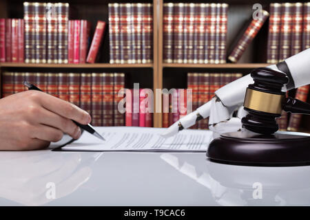 Roboterhand Unterstützung der Person, die für die Unterzeichnung dieses Dokuments reflektierende Schreibtisch Im Gerichtssaal Stockfoto