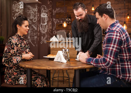 Kellner, das junge Paar mit Croissants. Im schönen Pub Datum. Stockfoto