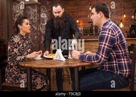 Kellner, das junge Paar mit Croissants. Im schönen Pub Datum. Stockfoto