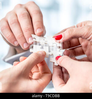 Schuss von konzeptionellen menschliche Hände Montage weiß Puzzleteile hautnah. Stockfoto