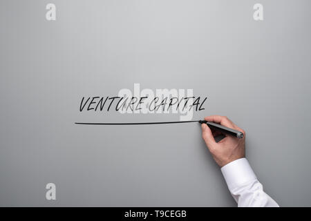 Hand eines Geschäftsmannes Schreiben einer Venture Capital Zeichen auf grauem Hintergrund mit grau Filzmarker ankreuzen. Stockfoto