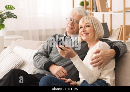 Gerne älteres Paar umarmen und Fernsehen Stockfoto