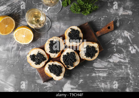 Köstliche Sandwiches mit schwarzen Kaviar und Glas Wein auf Graue Tabelle Stockfoto