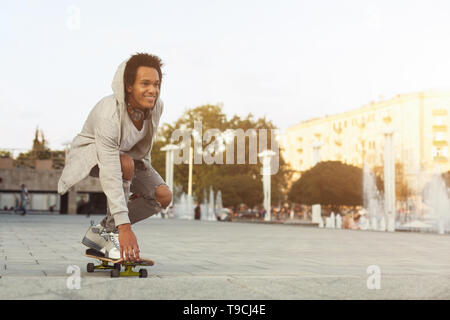 African American Teen Guy Skateboarding auf Sommer Abend Stockfoto