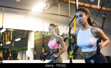 TRX Training. Mädchen trainieren mit Suspension Trainer im Fitnessraum Stockfoto