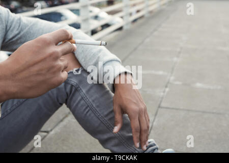 Jugendlich Ausgaben. Schwarzer jugendlicher Raucher Zigarette, allein sitzen Stockfoto