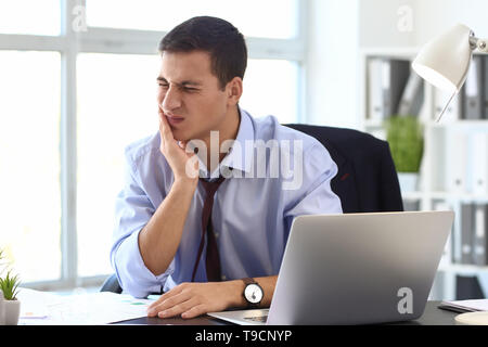 Junge Unternehmer leiden unter Zahnschmerzen im Büro Stockfoto