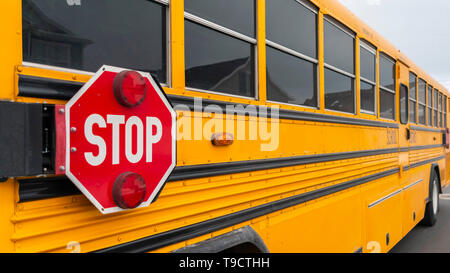 Panorama Außenansicht eines gelben Schulbus mit einem roten Stoppschild und Blinkleuchten Stockfoto