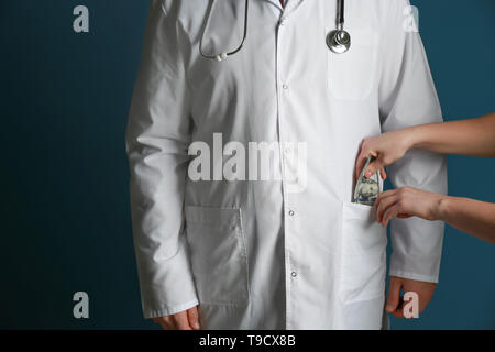 Frau Geld in der Tasche von Doctor's Mantel auf farbigen Hintergrund. Korruption Konzept Stockfoto