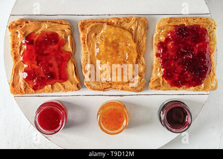 Leckere Toasts mit verschiedenen süßen Marmeladen auf dem Whiteboard Stockfoto