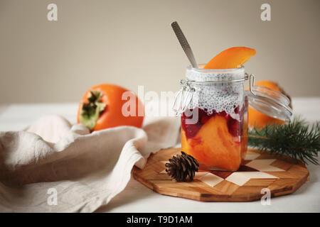 Leckere Dessert mit Reifen persimmon in Mason jar auf Holzbrett Stockfoto