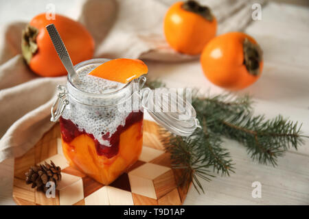 Leckere Dessert mit Reifen persimmon in Mason jar auf Holzbrett Stockfoto