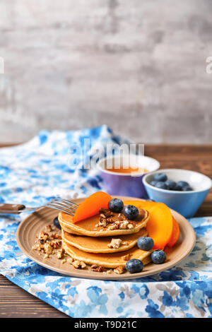 Hot leckere Pfannkuchen mit in Scheiben geschnittenen Kaki, Blaubeeren und Walnüsse auf Teller Stockfoto