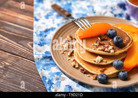 Hot leckere Pfannkuchen mit in Scheiben geschnittenen Kaki, Blaubeeren und Walnüsse auf Teller Stockfoto