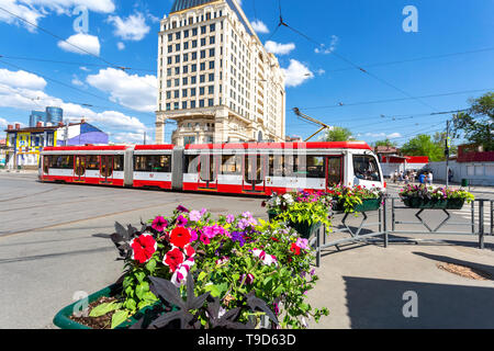 Samara, Russland - 9. Mai 2019: Stadtbild mit Blumen, rote Straßenbahn- und modernes Gebäude von Lotte Hotel Samara im Sommer sonnigen Tag Stockfoto