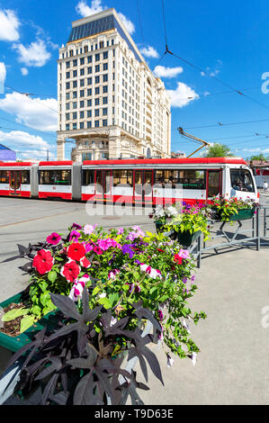 Samara, Russland - 9. Mai 2019: Stadtbild mit Blumen, rote Straßenbahn- und modernes Gebäude von Lotte Hotel Samara im Sommer sonnigen Tag Stockfoto