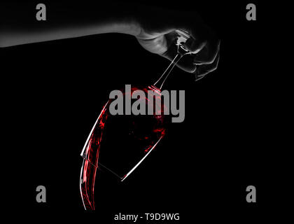 Weibliche Hand gießen Rotwein aus einem Glas, Konzept stop Alkoholismus, über schwarzen Hintergrund Stockfoto