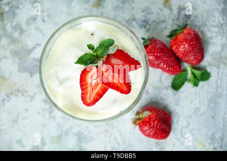 Eis mit Erdbeeren in einem Glas Vase. Grau strukturierten Hintergrund. Nachtisch. Ansicht von oben. Lebensmittelkette Stockfoto