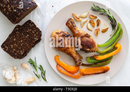 Fried Chicken, geröstete Paprika, Knoblauch und Rosmarin gebraten auf einer Platte oben Blick aus der Nähe auf weißem Hintergrund Stockfoto