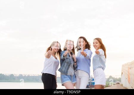 Glückliche Gruppe der weiblichen Freunde mit Daumen hoch im freien Blick auf Kamera und Lächeln. Stockfoto