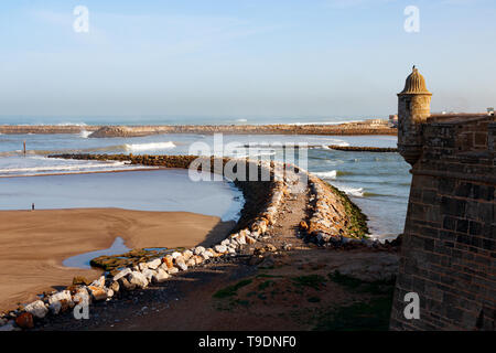 Mittelalterliche Mauer mit kleinen Türmchen der Kasbah des Udayas und eine Ansicht wellenbrecher, die Bou Regreg Mündung vom Atlantik getrennt. Stockfoto