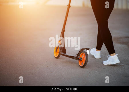 Frau mit einem Roller im Sommer auf dem Asphalt, croped Foto Stockfoto