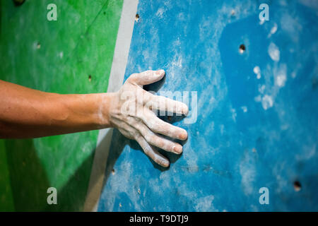 Ein Mann hält Kletterwand Steine im Startpunkt. Stockfoto