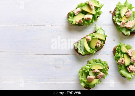 Sandwichs mit Thunfisch, Avocado und Salatblätter Öffnen über hellen Hintergrund mit kopieren. Lecker Thunfisch Brötchen zum Frühstück. Gesunde Snack Stockfoto