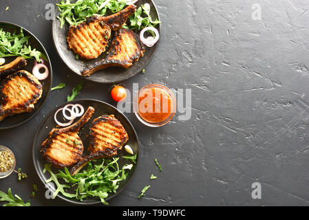 Gegrilltes Schweinefleisch Steaks auf schwarzen Stein Hintergrund mit kopieren. Ansicht von oben, flach Stockfoto