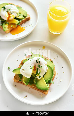 Frühstück mit pochierten Eiern auf geröstetem Brot und Orangensaft. Gesunde morgen essen. Ansicht von oben, flach Stockfoto