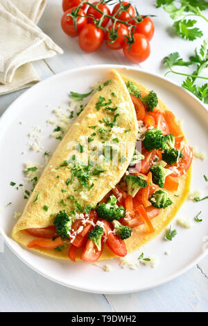 Omelett mit Tomaten, rote Paprika und Brokkoli auf hellem Holztisch. Gesunde Ernährung Essen zum Frühstück. Lecker morgen essen. Stockfoto