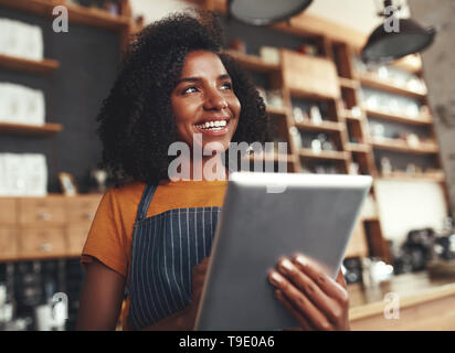 Eine afrikanische Frau Inhaber des Cafe Holding digital Tablet Stockfoto