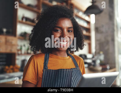 Glückliche junge Frau, die in Ihrem Cafe Stockfoto