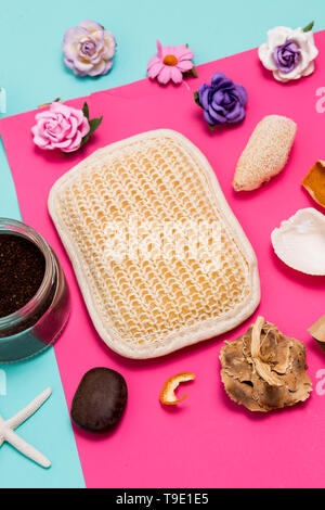 In der Nähe von Spa und Beauty Kosmetik Produkte auf bunten Blau und Rosa Hintergrund. Body und Face Scrub, natürliche Loofah Waschlappen, Muscheln, Steine und Stockfoto