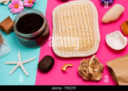 Nahaufnahme des bunten Spa- und Betreuungseinrichtungen, kleinen Blumen, schrubben, Waschlappen und Muscheln auf Rosa und blauen Hintergrund Stockfoto