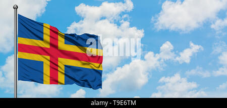 Aland Inseln Flagge im Wind gegen Weiße bewölkt blauer Himmel. Diplomatie Konzept, internationale Beziehungen. Stockfoto