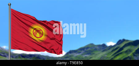 Kirgistan Fahne winken in den blauen Himmel und grüne Felder bei Mountain Peak im Hintergrund. Thema Natur. Stockfoto