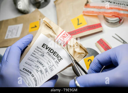 Wissenschaftlichen Polizei öffnet mit der Schere ein Beutel der Beweis eines Verbrechens im wissenschaftlichen Labor Stockfoto