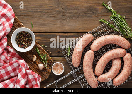 Rohe Würste vom Grill und Zutaten zum Kochen. Grill Vorbereitung. Holztisch. Platz für Text. Stockfoto