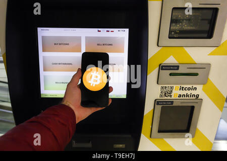 Prag, Tschechische Republik - 18. Mai 2019: Bitcoin ATM Maschine für den Kauf und Verkauf von cryptocurrency. Männliche verkauft Bitcoins von ATM mit Smartphone, Prag Stockfoto