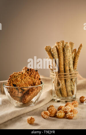 Stillleben mit Brot Sticks, oatmeal Cookies und breadballs. Grissini ist im Glas. Cookies sind in der Schüssel. Breadballs sind auf einem Hanf Tischdecke. Stockfoto