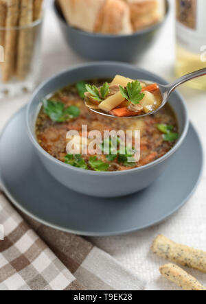 Der Löffel ist mit Pilz Suppe auf dem Hintergrund dieser Teller gefüllt. Im Vordergrund steht eine Küche Tuch und knusprige Grissini. Im Hintergrund Stockfoto