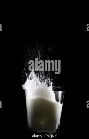 Gießen ein frisches Glas weiße Milch. Flüssigkeit eine große Welle. Verschüttete Milch in Zeitlupe spritzen aus dem Glas. Stockfoto