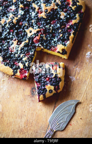 Close-up-Torte und ein Stück von berry Obstkuchen mit Blaubeeren und Erdbeeren auf Holz- Hintergrund Stockfoto