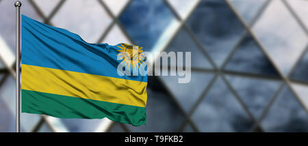 Ruanda Flagge im Wind gegen verwackelte, modernes Gebäude. Geschäftskonzept. Nationale Zusammenarbeit Thema. Stockfoto