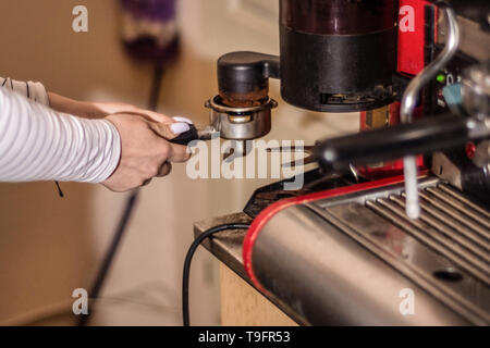 Mädchen, Espresso Kaffee auf eine professionelle Maschine in der Bar. Mädchen Hand Mühle Kaffee, der Espresso Kaffee auf der retro Maschine Stockfoto