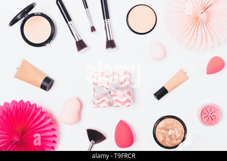 Festliche flachbild Layout der Make-up-Produkte und Geschenkbox mit Papier Dekorationen auf weißem Hintergrund, Ansicht von oben. Stockfoto
