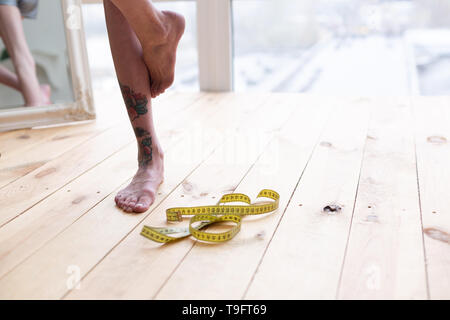 Skinny Frau auf einem Bein stehen nach ihrem Körper messen Stockfoto